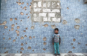 Döbbenetes fotó: kisfiú áll egy golyók szaggatta fal előtt 